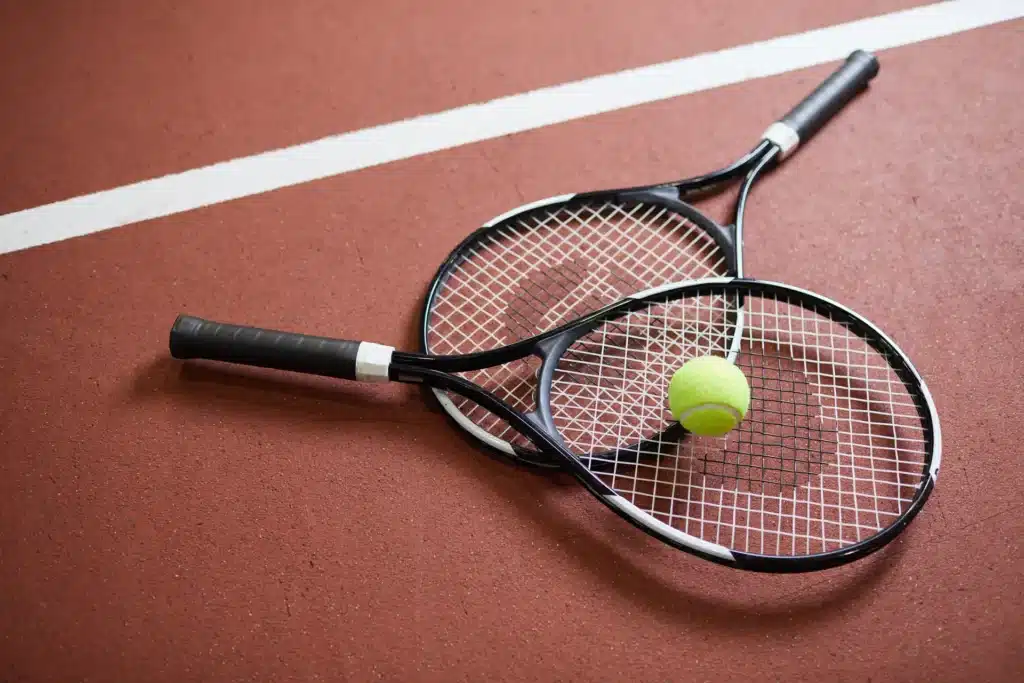 two tennis rackets and a tennis ball stacked on a tennis court
